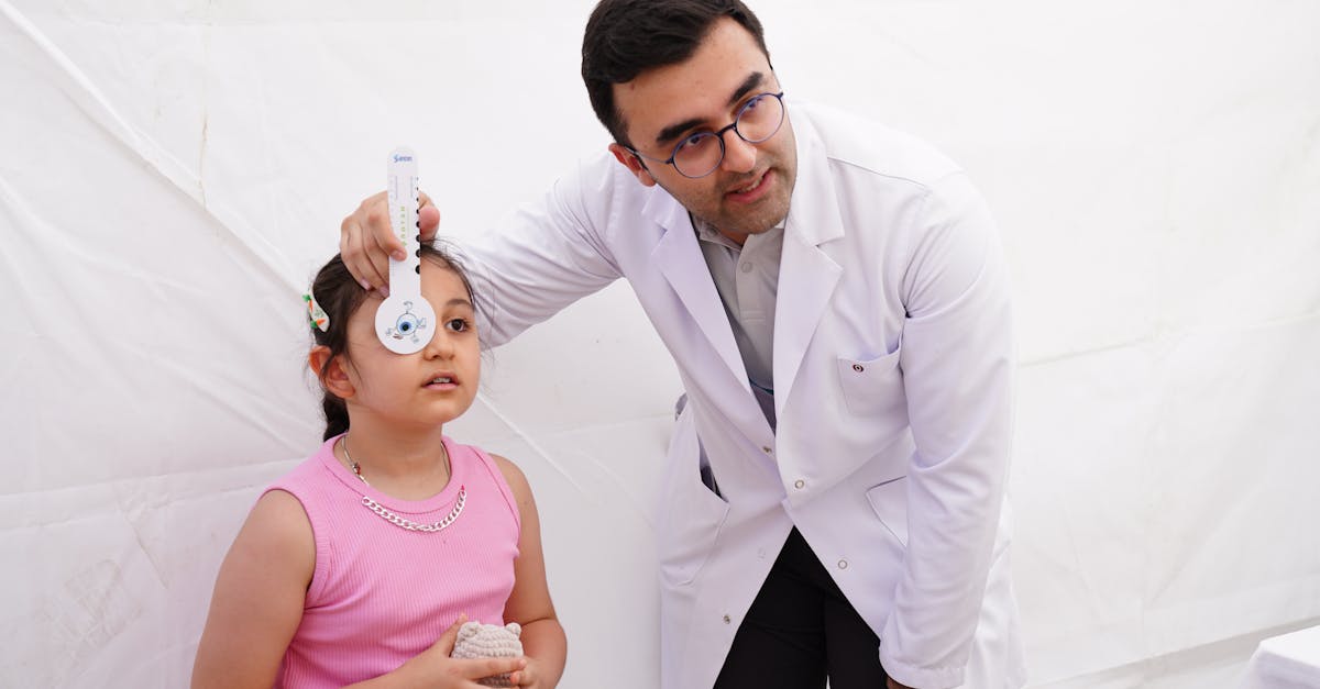 A doctor conducts a vision test on a young girl using an eye chart in a clinical setting.