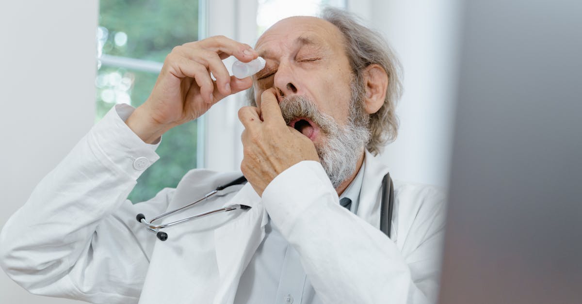 Elderly doctor applying eye drops, emphasizing eye care and senior health.
